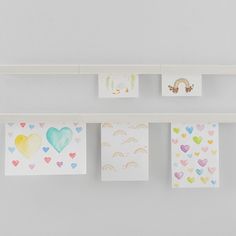 several cards hanging on a wall with hearts and rainbows