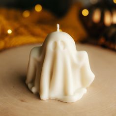 a small white candle sitting on top of a wooden table next to a gold cloth