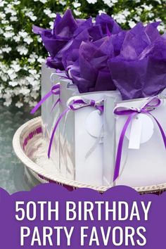 purple and white birthday party favors sitting on top of a cake plate with flowers in the background