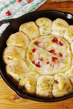 a pan filled with bread and cheese on top of a wooden table next to a towel