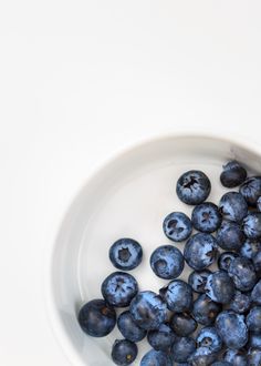 blueberries are in a white bowl on the table