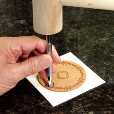 a person using a wood carving tool on a piece of paper