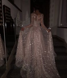 a woman in a long dress is walking down the stairs