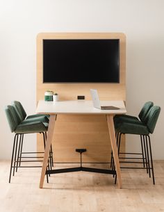 a desk with two chairs and a laptop on it in front of a wall mounted screen