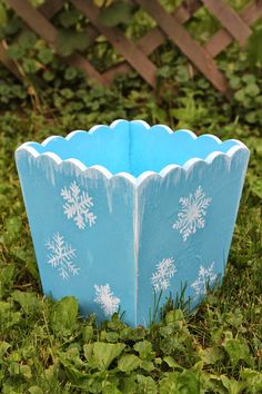 a blue cup sitting in the grass with snowflakes on it