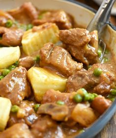 a bowl filled with meat and potatoes on top of a wooden table