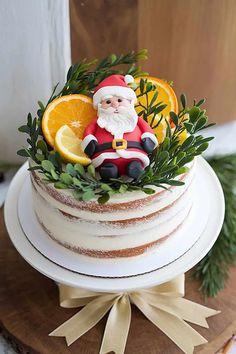 a christmas cake with orange slices and santa clause decoration on top, surrounded by greenery