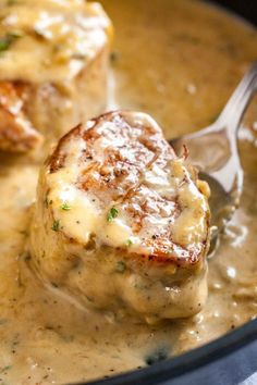 two meatballs covered in gravy with a spoon sticking out of the top