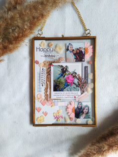 a photo frame hanging on a chain with flowers and hearts attached to the back of it