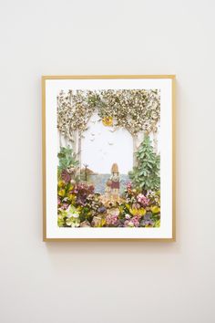 a painting hanging on the wall next to a vase with flowers and plants in it