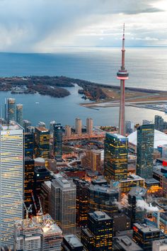 an aerial view of a city with tall buildings and the ocean in the background at dusk