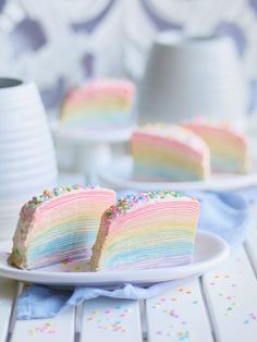 a slice of rainbow cake with sprinkles on a plate next to a cup