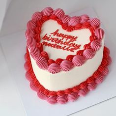 a heart shaped birthday cake on a white table