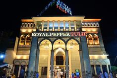 the royal pepper tulip hotel is lit up at night with people walking in front