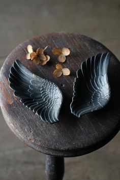 two pieces of metal sitting on top of a wooden table with nuts in the shape of wings