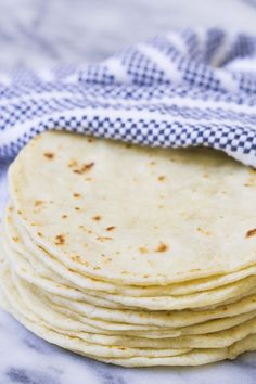 a stack of tortillas sitting on top of a blue and white checkered cloth