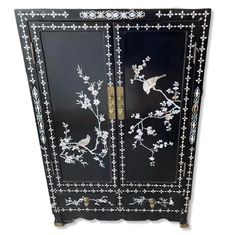 a black cabinet with white flowers and birds on it