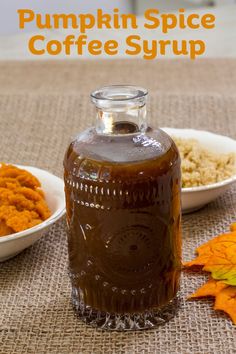 a bottle of pumpkin spice coffee syrup next to two white bowls with fall leaves on the table