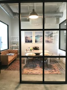 an office with a couch, table and chairs in front of glass doors that lead into the living room