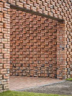 a brick building with an open door on the side and grass in front of it