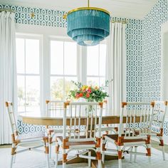 a dining room with blue and white wallpaper, chairs and a table in front of a large window