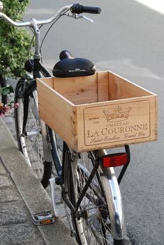 a bicycle with a wooden crate attached to the front rack and handlebars is parked next to a sidewalk