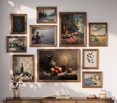 a wall filled with pictures and paintings next to a table