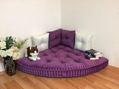 a purple couch sitting on top of a wooden floor next to a vase filled with flowers