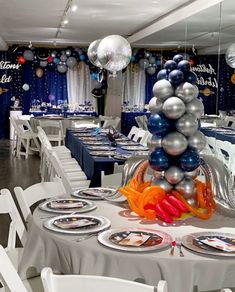 a table set up with silver and blue balloons