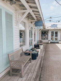 two wooden benches sitting on the side of a building next to a store front with blue shutters