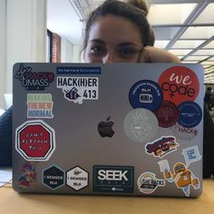 a woman sitting in front of a laptop covered in stickers