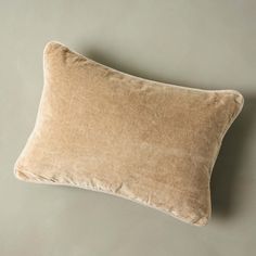 a tan pillow sitting on top of a gray wall