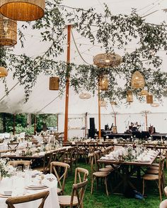 an outdoor tent with tables and chairs set up for a wedding reception under hanging lights