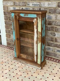 an old wooden cabinet sitting in front of a brick wall with tile flooring on it