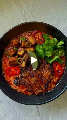 a bowl filled with meat and vegetables on top of a white tablecloth covered table