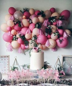 an image of a cake with balloons on it and pink tassels hanging from the ceiling