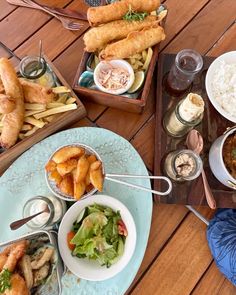 there are many different types of food on this wooden table, including breads and salads