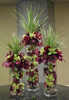 three vases filled with flowers and plants on a table