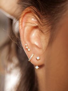 a close up of a person with ear piercings on their ears and wearing gold jewelry