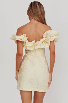 the back of a woman wearing a short dress with ruffles on it and one shoulder