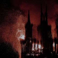 fireworks are lit up in the night sky behind gothic - styled buildings with spires