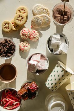 many different desserts are on the table with cups and spoons next to them