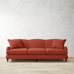 an orange couch sitting on top of a hard wood floor next to a white wall