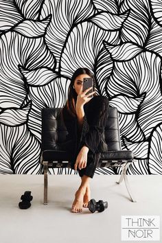 a woman sitting in a chair taking a selfie with her cell phone while wearing black shoes