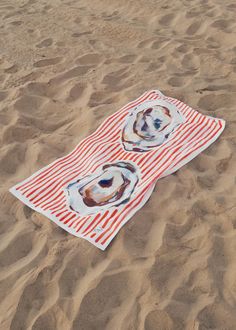 an orange and white towel laying on top of sand