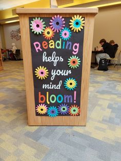 a sign that says reading helps your mind bloom on the side of a wooden podium