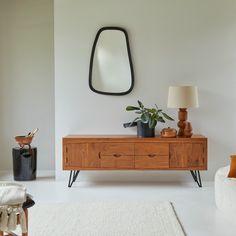 a living room with a white rug and a wooden dresser in the corner next to a mirror