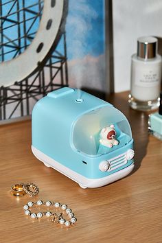 a small blue toaster sitting on top of a wooden table next to some rings