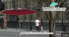 people are walking down the street with umbrellas over their heads and in front of an iron fence