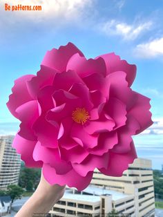 a person holding up a large pink paper flower